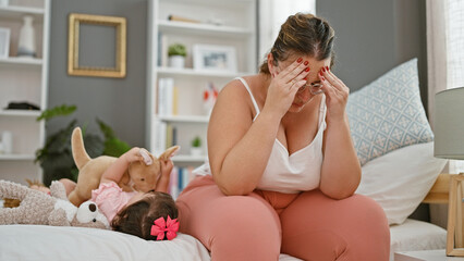 Stressed mother and daughter sitting on bed, playing with toys in a bedroom - a reflecting moment of indoor family life