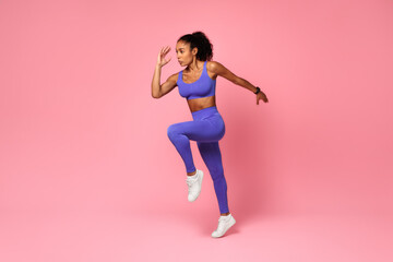 Fototapeta na wymiar Athletic African Lady Jumping Exercising During Training Over Pink Background