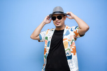 Fototapeta premium asian man wearing beach shirt pointing a finger to vacation discount offer. Isolated on blue background. Vacation concept