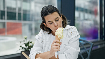 Beautiful young hispanic woman eating ice cream at cafeteria