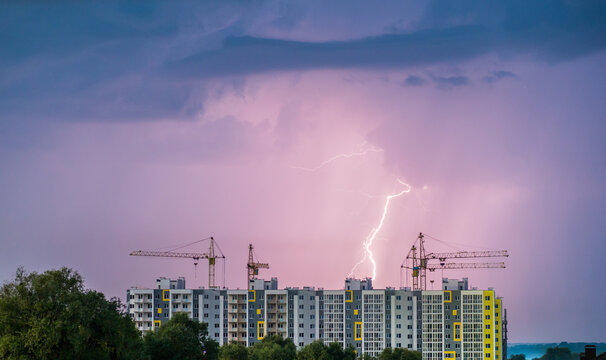 Lightning cuts the sky, in the foreground the construction of multi-storey residential buildings