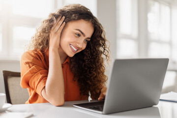 Smiling curly woman with laptop in office