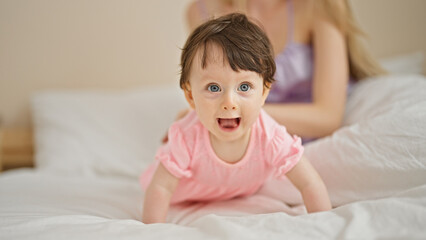 Mother and daughter crawling on bed at bedroom