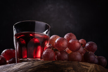 a glass of wine and red grapes on a dark background. - 685824356