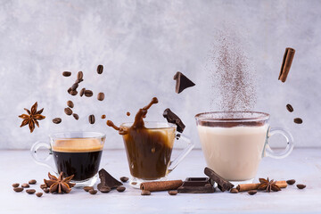 lively composition with espresso, latte and cappuccino in transparent glass cups among floating aromatic spices, chocolate pieces and coffee beans
