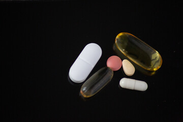 close up of different tablets and pills on the black background
