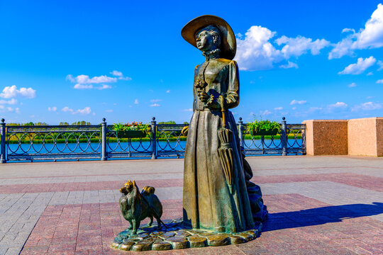 Astrakhan, Russia, September 28, 2023. Sculpture Lady with a dog on the Petrovskaya embankment of the Volga River against the background of the sky and clouds.