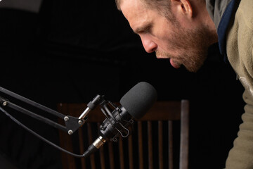 White man speaking to a microphone isolated on dark background, hipster look