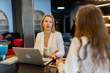 Fototapeta premium Employees cooperate for teamwork at shared modern workspace. Female managers talk during break at shared workspace in business company