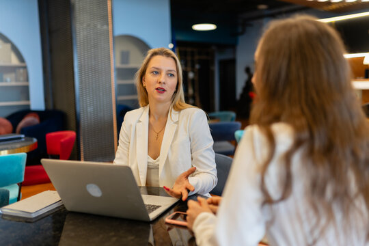 Employees cooperate for teamwork at shared modern workspace. Female managers talk during break at shared workspace in business company