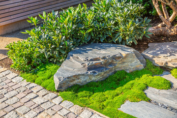 Detail of garden path with stone slabs with bark mulch and native plants. Landscaping and gardening...