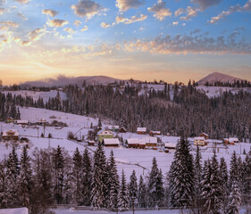 Pre-dawn alpine small quiet village and winter snowy mountains around