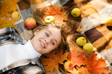 Top view of a young girl lying on a plaid plaid and apples scattered everywhere, a beautiful autumn...