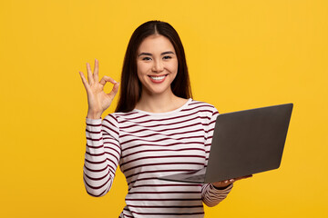 Positive young chinese lady student posing with laptop