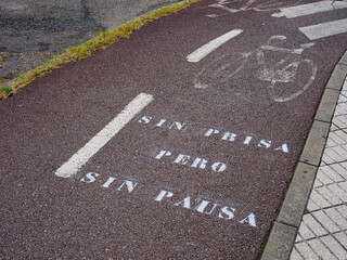 Bicycle lane with motivational phrase painted on the ground, meaning "Without rush but without pause."