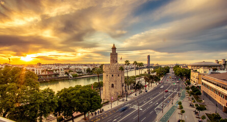 Vista dramática de la Torre del Oro y Río Guadalquivir de Sevilla al atardecer con nubes en el cielo - obrazy, fototapety, plakaty