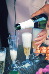 Pouring champagne into a glass for guests at a wedding