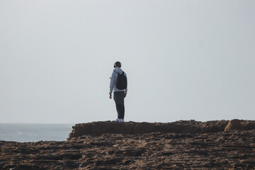 Young man standing on the top of a rock in a beach