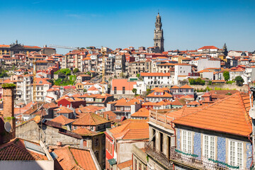 Fototapeta na wymiar View across the tiled roofs of Porto, Portugal, on a fine spring day. The skyline is dominated by the tower of the Igreja dos Clérigos, the Church of the Clerics.