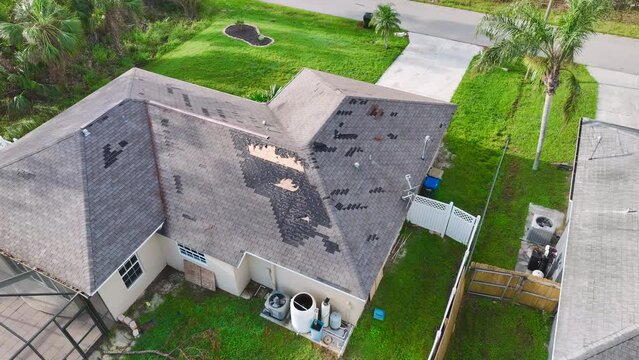 Top view of leaking house roof covered with protective tarp sheets against rain water leaks until replacement of asphalt shingles. Damage of building rooftop as aftermath of hurricane Ian in Florida