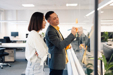 A multiracial businesspeople writing on sticky notes at corporate firm.