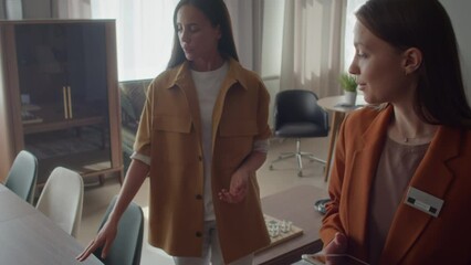 Tracking shot of potential buyer walking around furniture retail, asking sales manager questions while looking out for necessary pieces