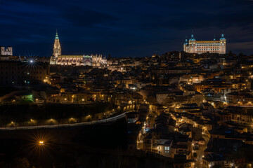 Fototapeta na wymiar Historic center of Toledo, Spain, at night with the light of street lamps and the cathedral and Alcazar (army museum) illuminated. UNESCO World Heritage Site