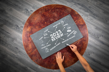 2023 Review concept. Chart on chalk board. Round wooden table