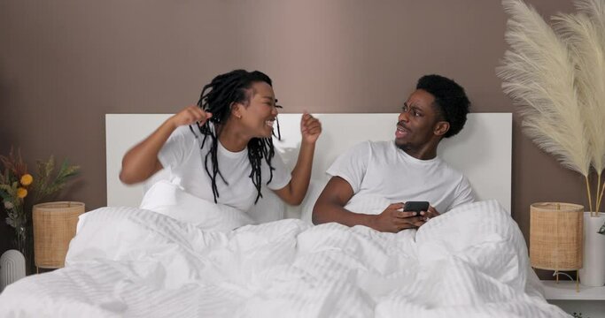 Furious disappointed african american dark skinned woman wife arguing blaiming her husband in treason unhappy young black family concept sitting in bed in the morning. Female gesticulating shouting.