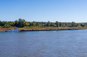 Obraz premium Large tug boat pushing rows of barges with coal products down the Mississippi river south of Cairo in Illinois