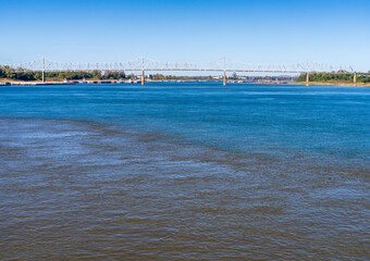 Barges wait at the confluence of the blue Ohio river and brown Mississippi river at Cairo with blue...