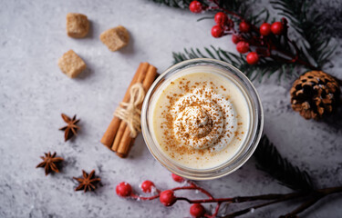 Obraz na płótnie Canvas Eggnog with cinnamon decorated with whipped cream in a glass