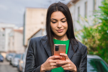 Fototapeta premium urban latin hispanic woman with leather jacket using mobile phone on the street