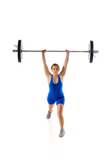 Competition. Full-length of young woman in sportswear, lifting heavy barbell against white background. Concept of sport, strength, gym, healthy lifestyle, power and endurance, weightlifting.