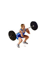 Concentrated strong young woman, athlete training doing squats, lifting heavy barbell against white background. Concept of sport, strength, gym, healthy lifestyle, power and endurance, weightlifting.