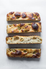 homemade olive focaccia on a white background, Flatlay of focaccia with green olive topping, fresh homemade focaccia bread