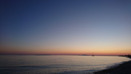 Fototapeta premium a small sailing ship sails into the dusk