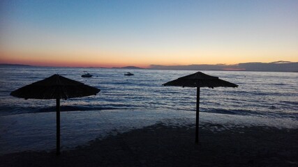 Straw umbrellas on the beach at dusk