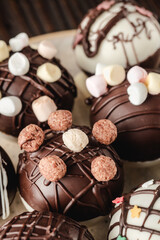 Chocolate bomb with cocoa powder and mini marshmallow to prepare a fragrant hot drink. On dark wooden background.
