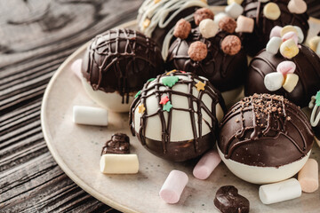 Chocolate bomb with cocoa powder and mini marshmallow to prepare a fragrant hot drink. On dark wooden background.