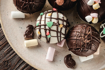 Chocolate bomb with cocoa powder and mini marshmallow to prepare a fragrant hot drink. On dark wooden background.