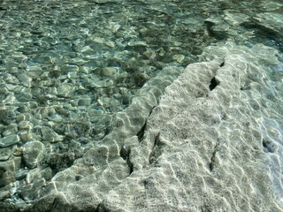 Pebbles stones in sea clear water with transparent surface.
