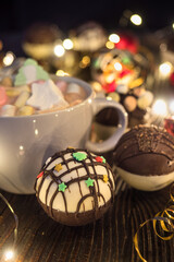Chocolate bomb with cocoa powder and mini marshmallow to prepare a fragrant hot drink. On dark wooden background.