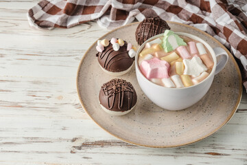 Chocolate bomb with cocoa powder and mini marshmallow to prepare a fragrant hot drink. On white wooden background.