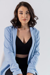 Obraz premium Beautiful young girl in black trousers and a blue jacket on a white background. Portrait of a beautiful young woman