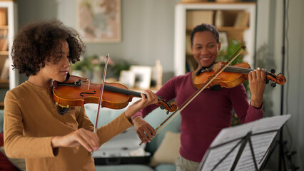 Mother and teenage boy playing violins at home