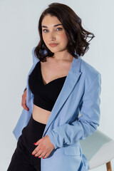 Beautiful young girl in black trousers and a blue jacket on a white background. Portrait of a beautiful young woman
