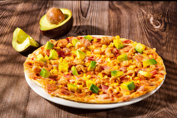 Pizza served with sausage, bacon, chicharron, sweet corn and pieces of avocado on a base of Neapolitan sauce and cheese