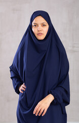 Portrait of young calm woman in hijab posing against background of studio