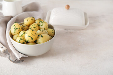 Bowl with boiled baby potatoes on light background